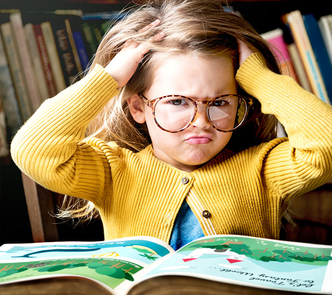 Little girl struggles reading, and looks frustrated